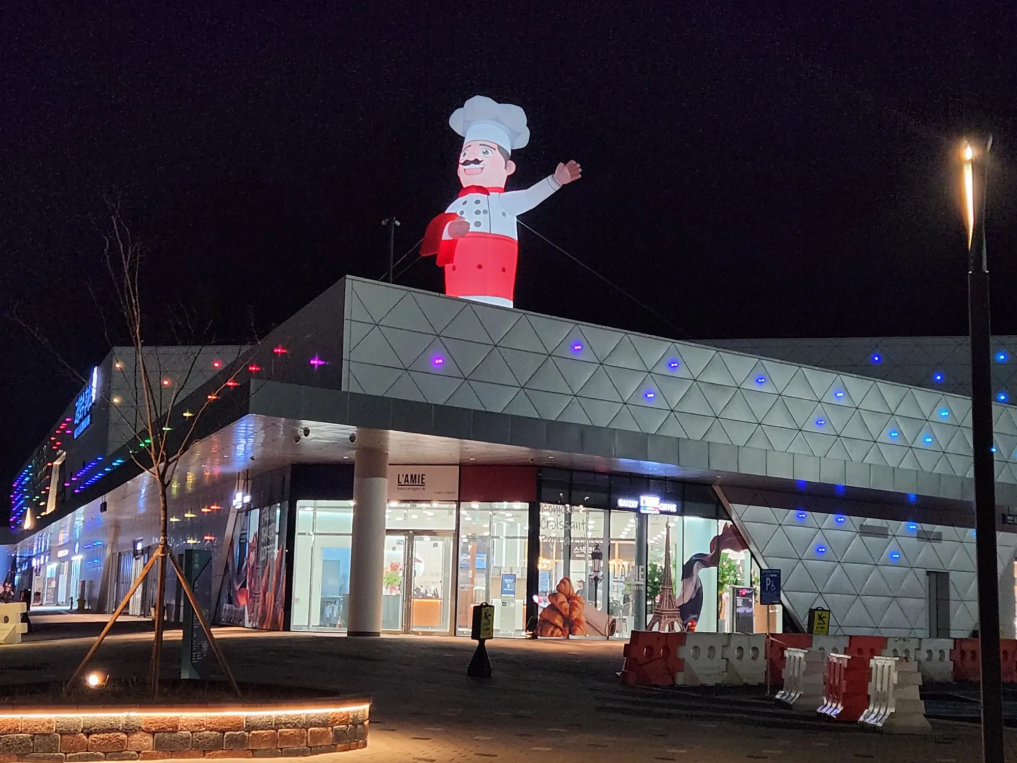 야간에 조명이 켜진 대형 캐릭터 에어조형물이 건물 위에서 환하게 빛나는 모습