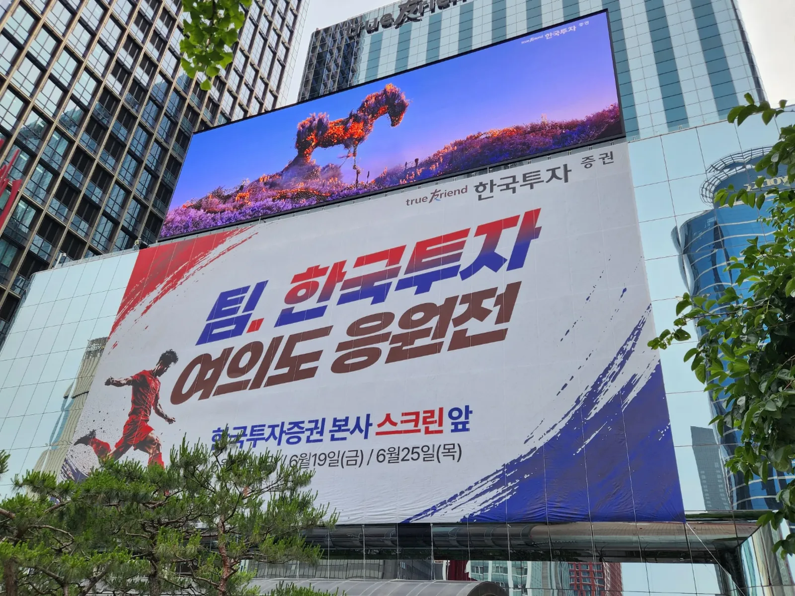 건물 외벽 대형 전광판과 현수막이 함께 노출된 완공 모습