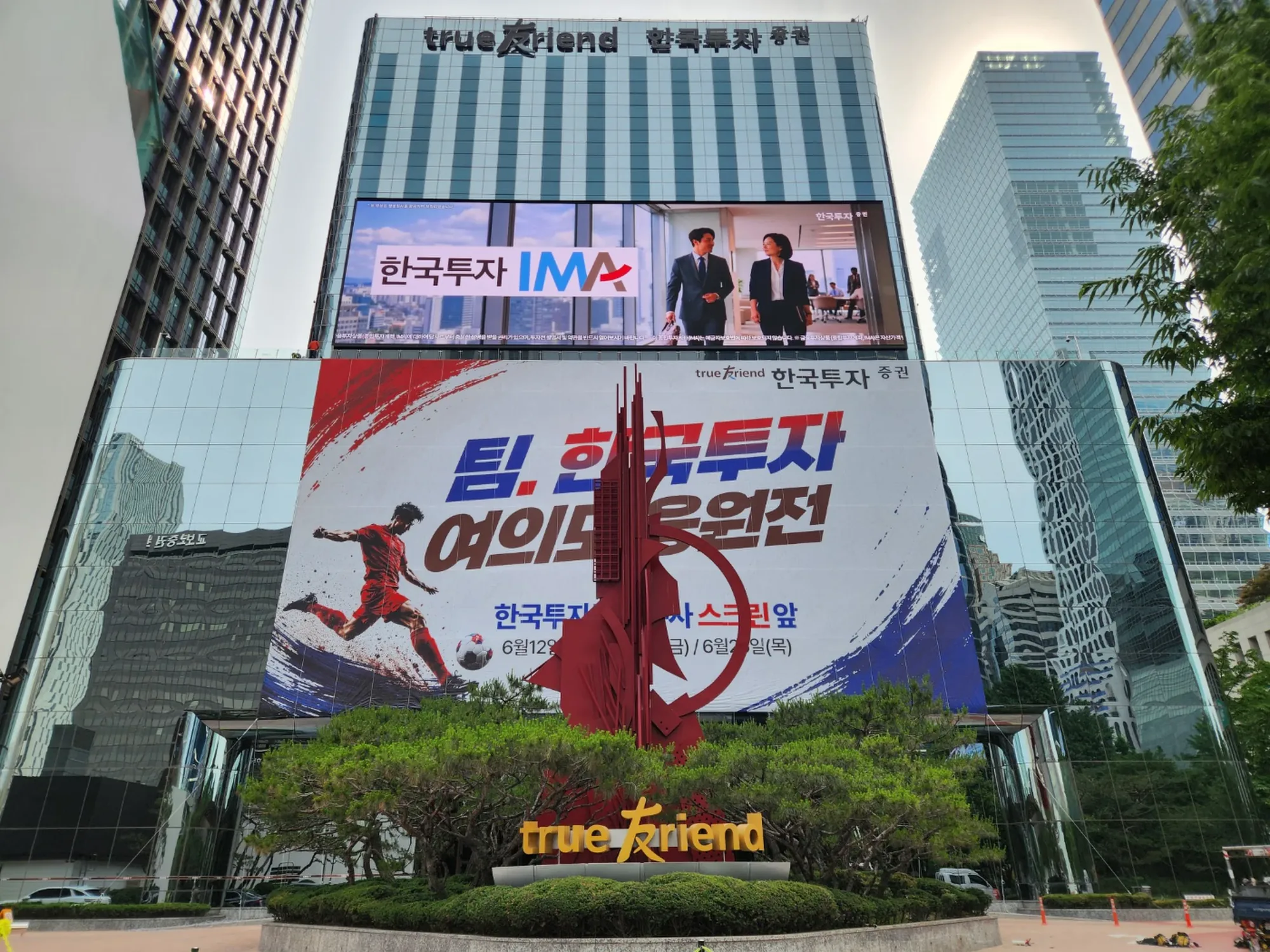 완공된 대형 응원 현수막이 설치된 고층 건물 외벽, 거리에서 바라본 전경
