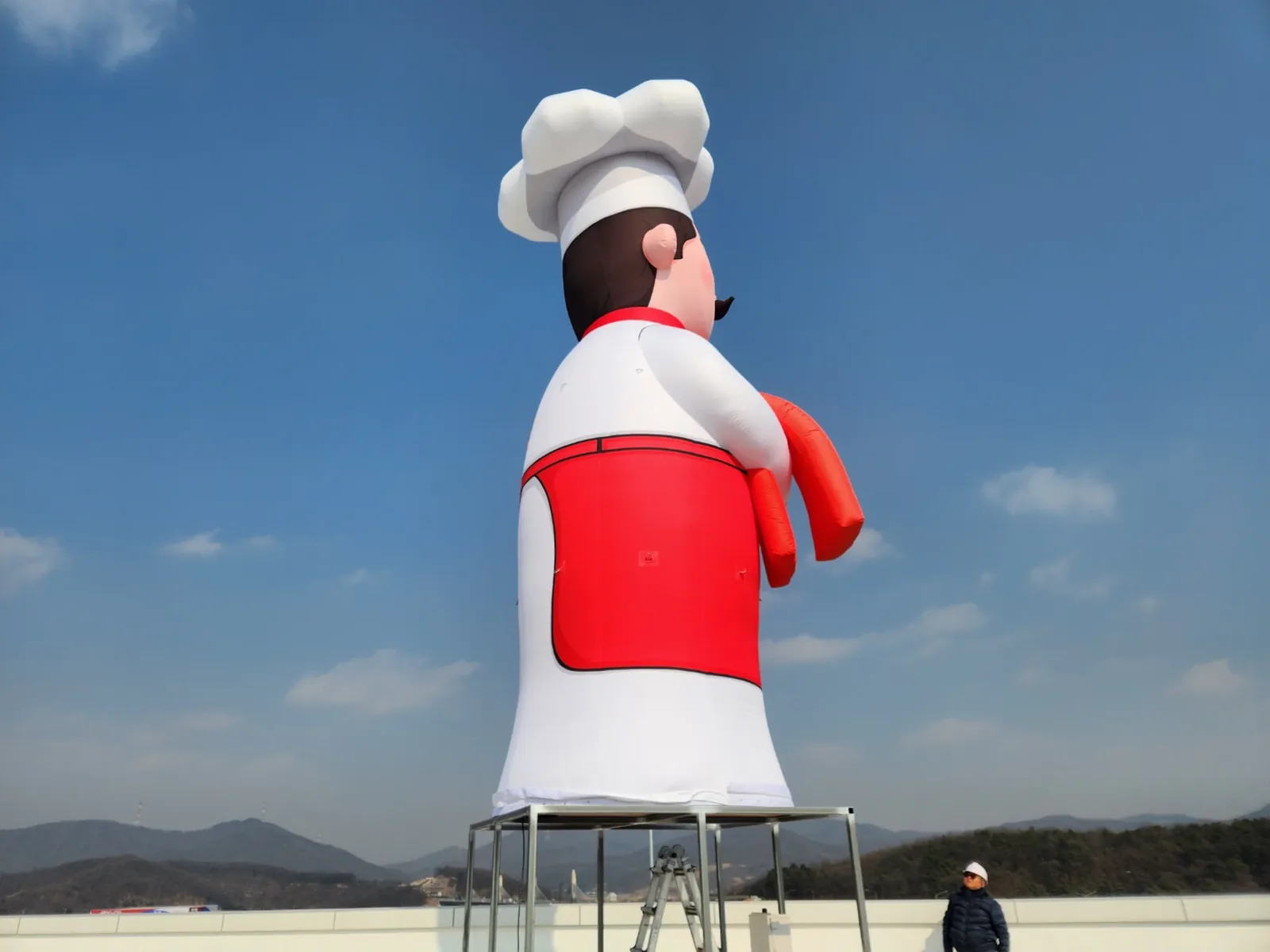 완공된 대형 에어셰프조형물이 옥상 위에 우뚝 설치된 모습, 맑은 하늘 배경